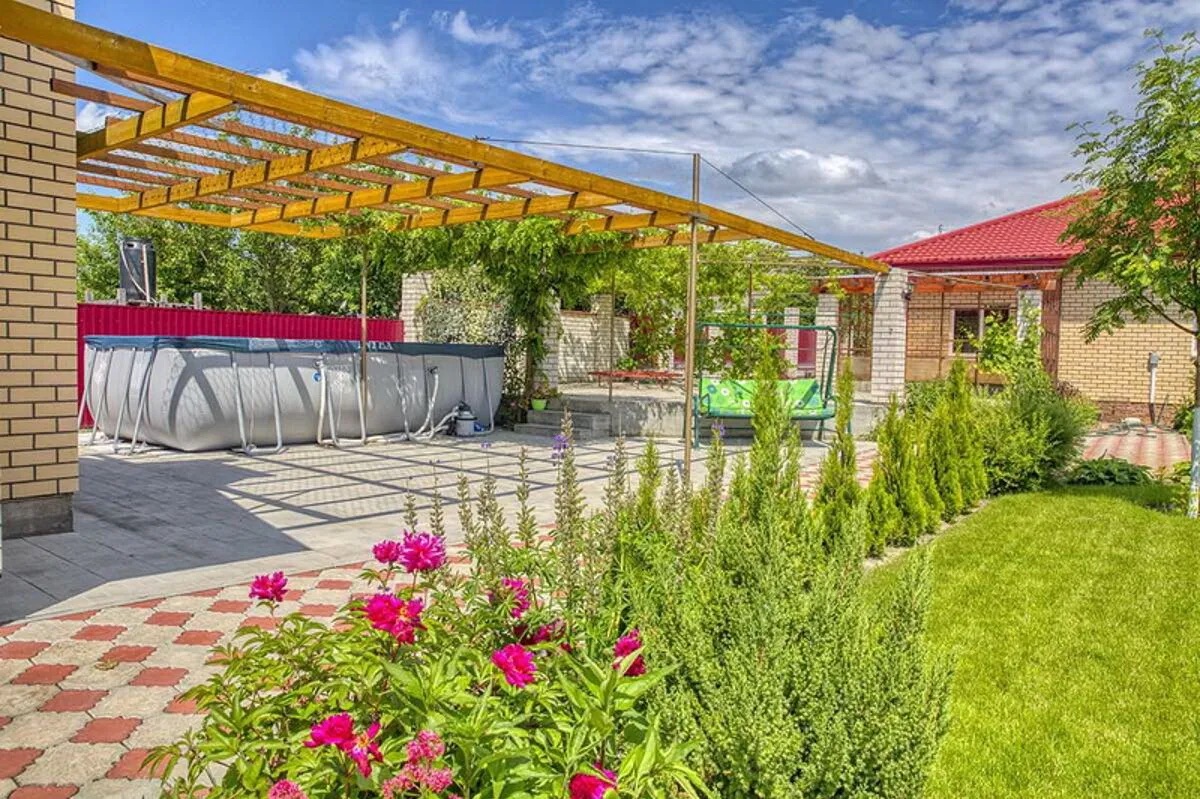 Летняя кухня с навесом, комфортная зона отдыха и бассейн во дворе дома.