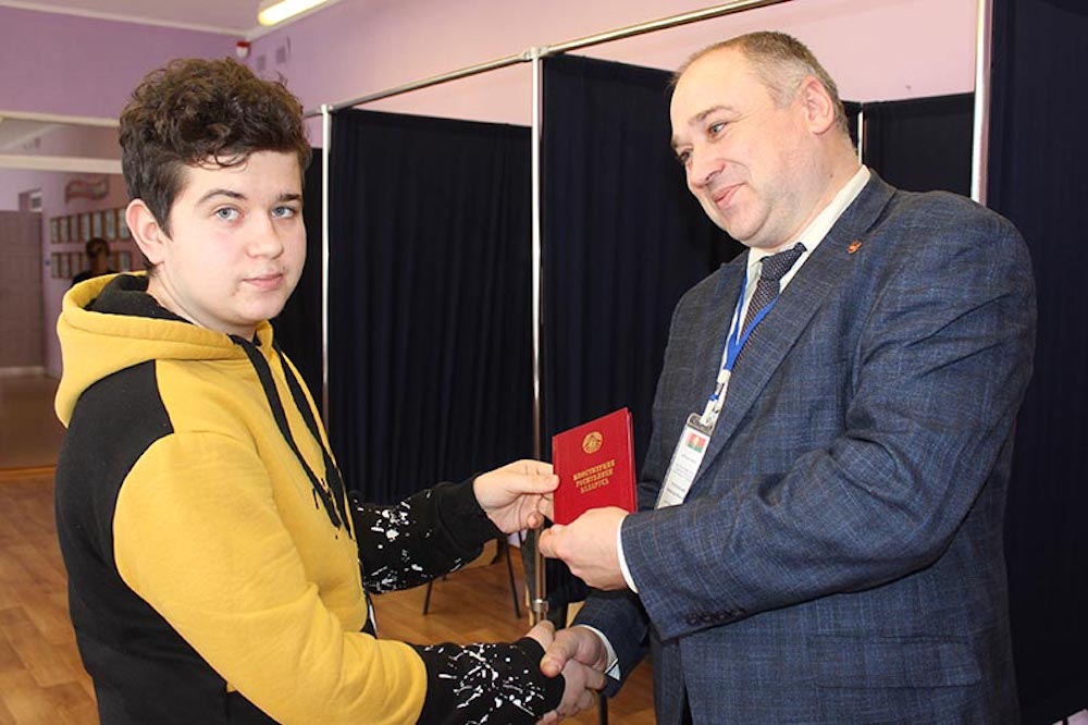 Председатель избирательной комиссии Александр Трояновский вручает Артему Полешуку подарочный экземпляр Конституции Республики Беларусь на избирательном участке № 1 в г. Ганцевичи. 22 февраля 2024 года. Фото:gants.by.