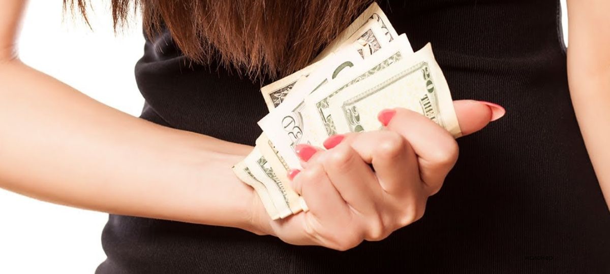 Девушка прячет деньги за спиной. Иллюстративное фото