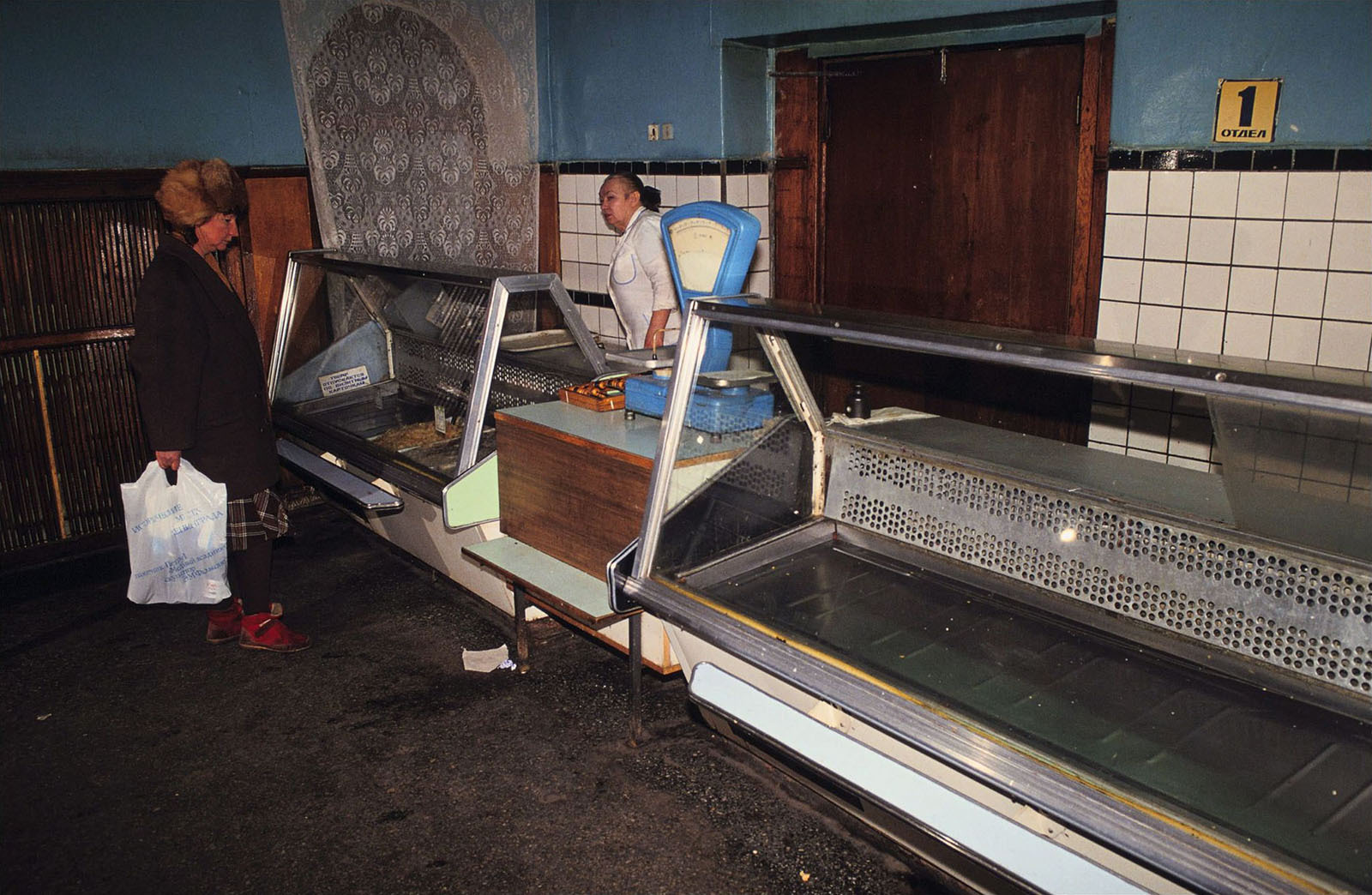 Советский магазин с пустыми витринами и покупательницей у прилавка, 1980-е годы