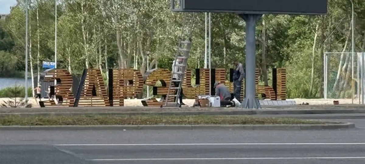 Билборд на фоне надписи с названием пляжа в Бресте. Фото: БрестСити